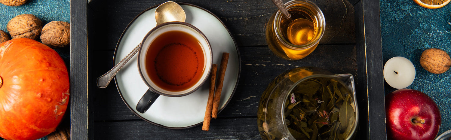 a fall spread of tea, apples, and pumpkin on a wooden tray