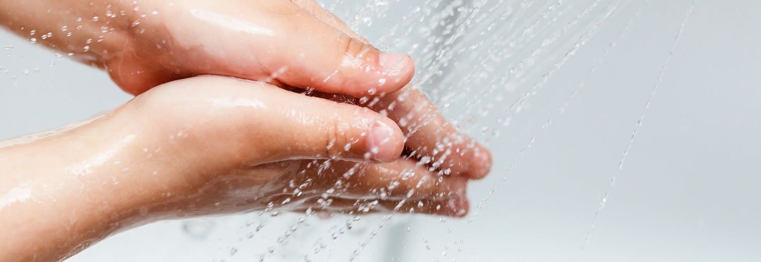 closeup of a woman's hands under running shower water