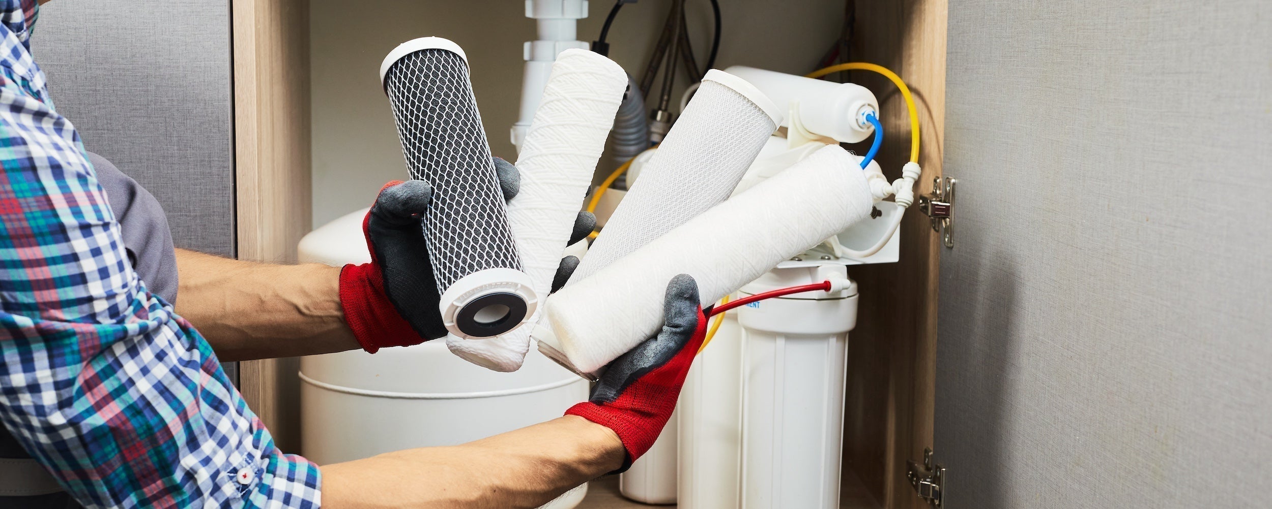 A plumber holding up various water filter replacements
