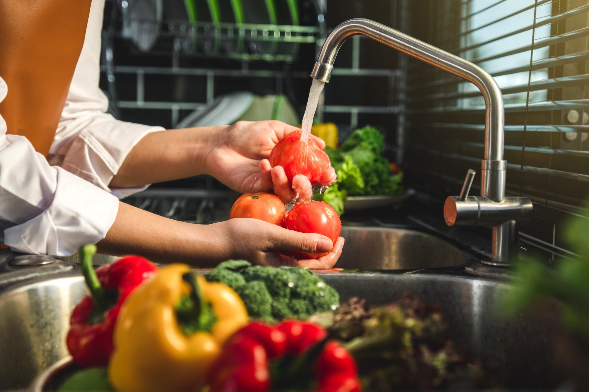 woman washing vegetables in kitchen sink