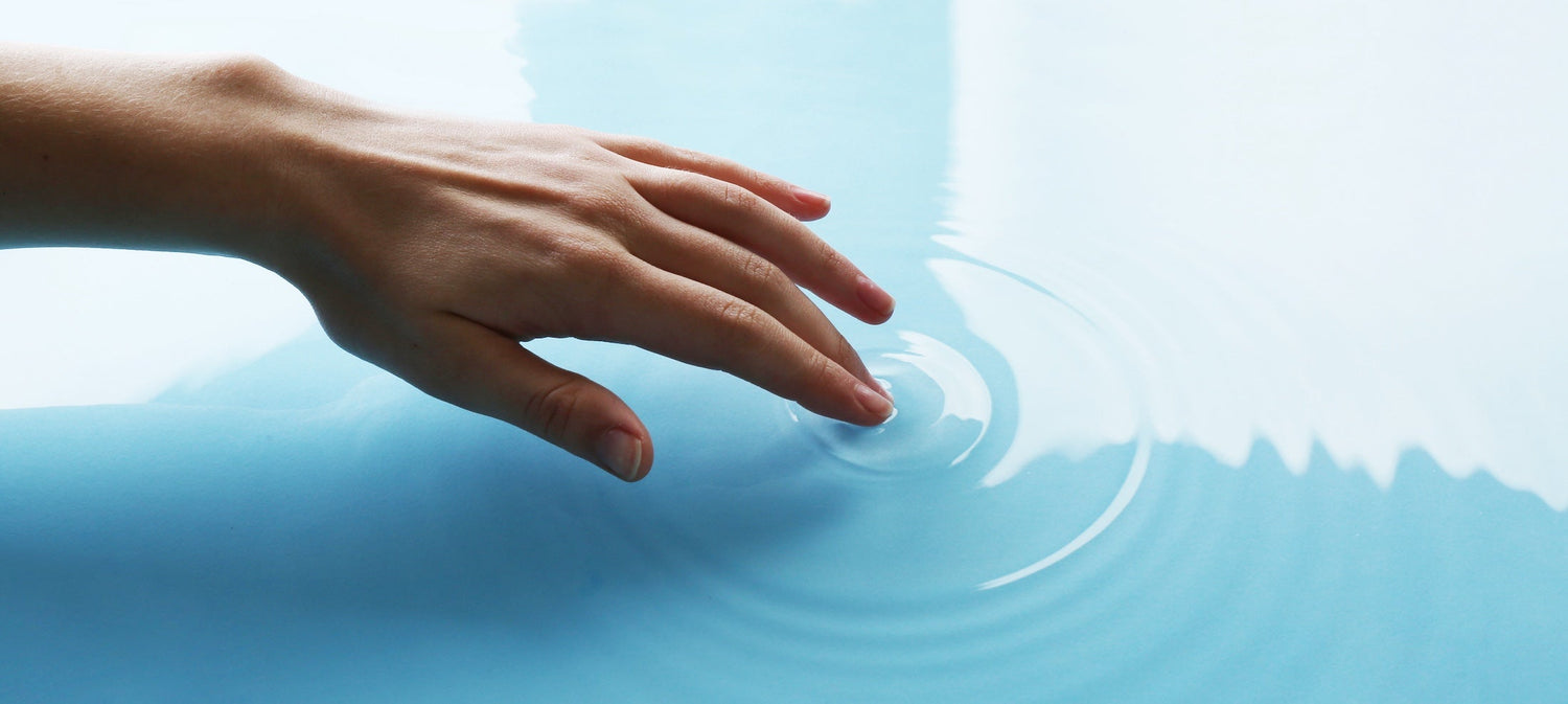 a closeup of a hand touching water and making a ripple effect from touching the surface