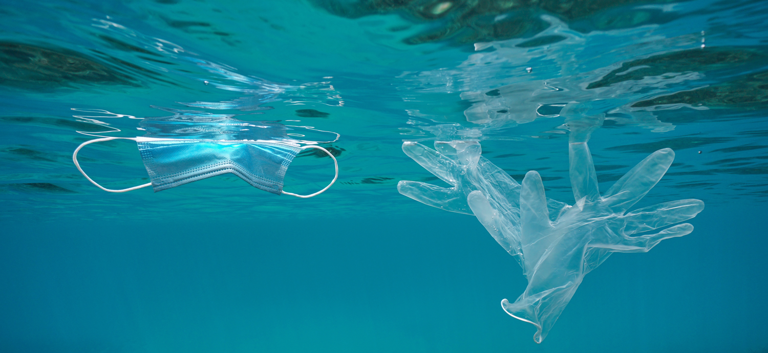 A disposable face mask and plastic gloves floating in water, symbolizing COVID-19 contamination and its impact on home water sources.