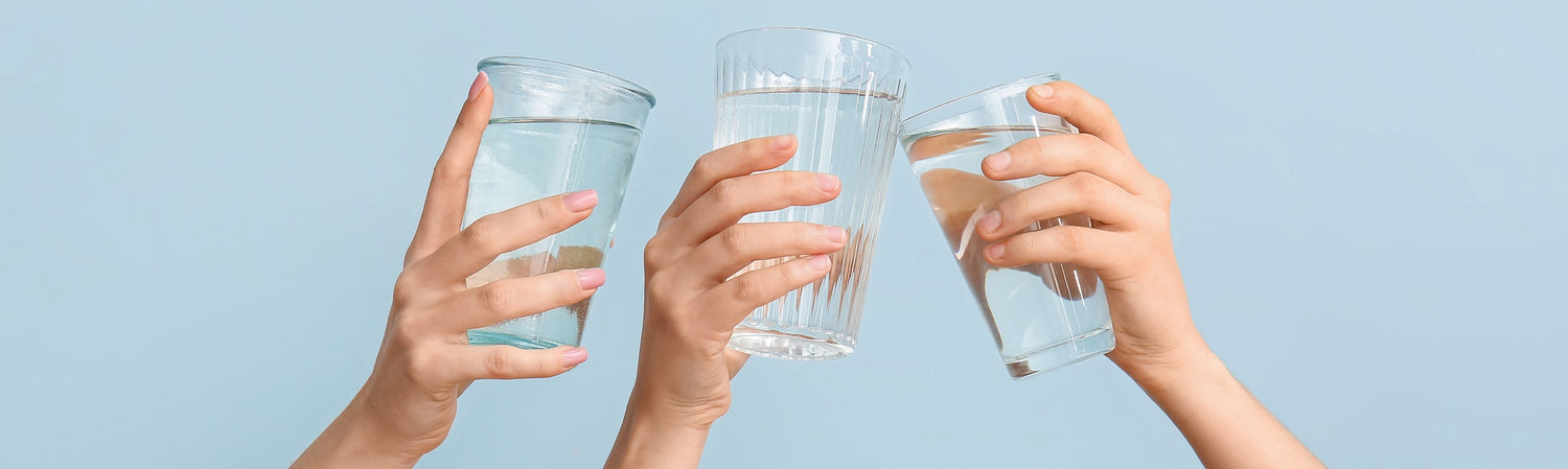 3 hands holding glasses of water with a light blue background