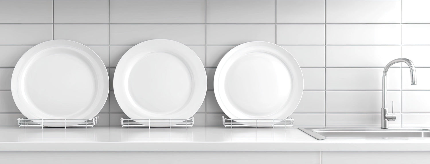 Elegant white plates resting in a dish rack on a sleek kitchen counter with a faucet in a modern, minimalistic setting